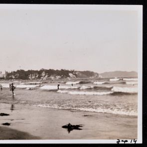 Beachgoers bathe in the shallow waters of the bay