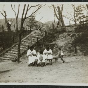 Gyermekek és gondozónőik egy parkban, út közelében, Uji