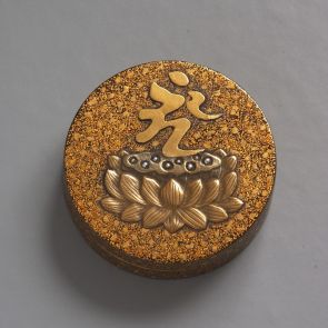 Kerek illatszeres dobozka (kōgō) tetején lótusztrón, fölötte az „ÓM” szanszkrit szótag ábrázolása
