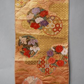 Japanese obi design sample with flowers  and tsuyu shiba pattern in front of golden and orange background