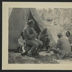 Baktay smokes a pipe in front of his tent among his friends