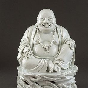 Budai sitting on a rock with his sack in his right hand