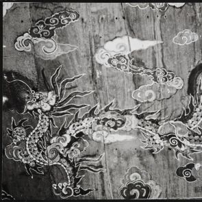 Fekete-fehér fotó festett sárkányokkal díszített falfelületről