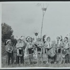 Eight Indians in front of the totem pole