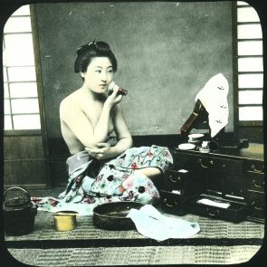A Japanese woman primping herself in front of a small mirror