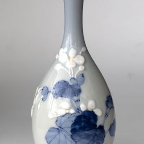 Porcelánváza virágos-leveles motívumokkal díszítve, részben domború mintával, részben máz alatti kék festéssel