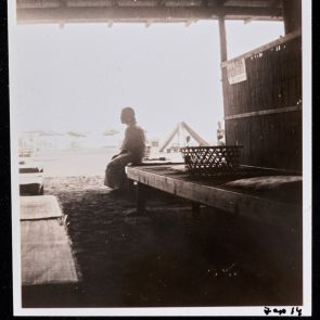 Woman in a kimono in the shade of an open pavilion on the beach