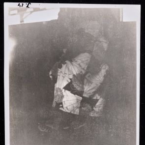 A kimonó krizantém és legyezőmintája villan elő a homályból, amint a hölgy hajóra száll