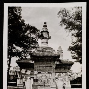 A decorative gate stands in front of the stupa of Huang-se Monastery (with votive flags along the road)