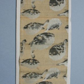 Textile sample - Woven decoration of silver-white and brown fish against drab background, mounted on cardboard