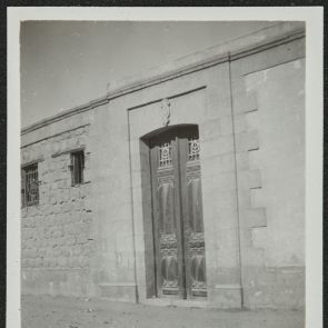 Díszes kétszárnyú ajtó vezet egy kőházba