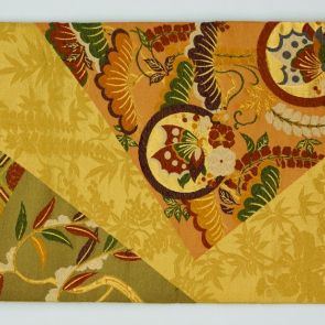 Japanese obi design sample with flowers and butterfly pattern in front of golden and dark orange background