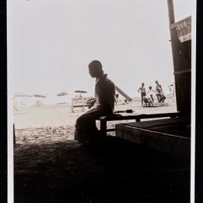 Woman in a kimono in the shade of an open pavilion on the beach