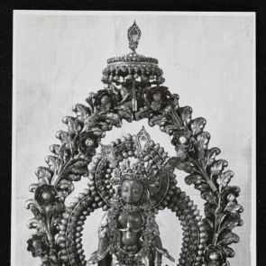Black and white photo of a statue of a goddess standing on a high pedestal in front of a double glory